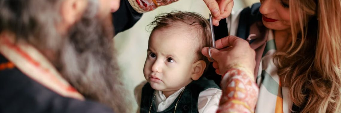 A baby's first haircut performed during a religious ritual with parents and clergy present.